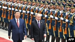 Russian President Vladimir Putin walks past a guard of honor with his Chinese counterpart, Xi Jinping, in Beijing last year. A new report says China has been bypassing EU sanctions in supplying Moscow with numerous goods used for military purposes. (file photo)