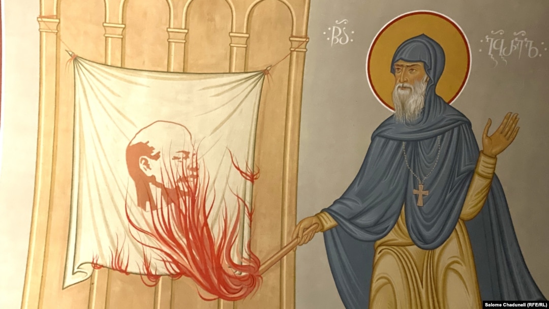 Стенопис изобразява грузинския монах Гавриил Ургебадзе, който подпалва знамето с лика на Владимир Ленин.