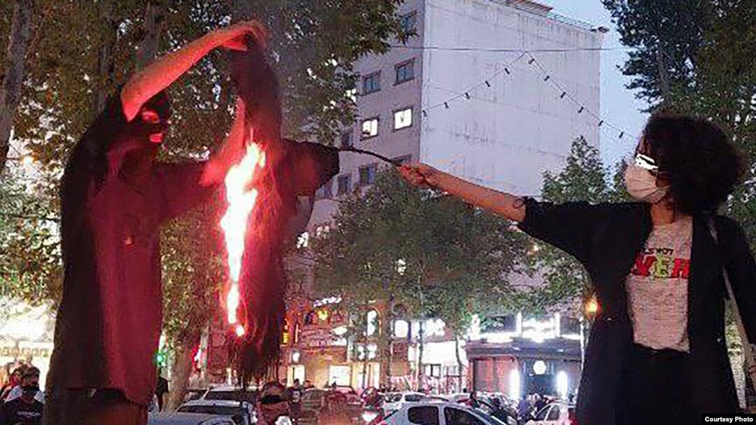 A woman sets fire to a headscarf in Iran during a recent protest.