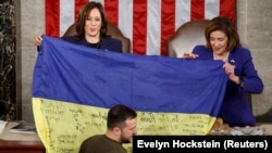 Тодішня спікерка Палати представників США Ненсі Пелосі (праворуч) і віцепрезидент США Камала Гарріс тримають український прапор з Бахмуту, який передав Конгресу США президент України Володимир Зеленський. Вашингтон, 21 грудня 2022 року