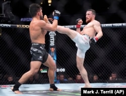 Merab Dvalishvili (dreapta) îl lovește cu piciorul pe Henry Cejudo în timpul meciului lor la categoria bantamweight din cadrul UFC 298 din California.