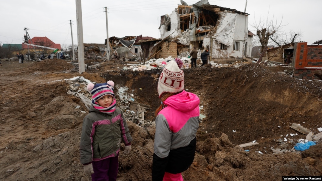 Children stand next to a crater left by a Russian military strike in the town of Hlevakha, outside Kyiv, on January 26.