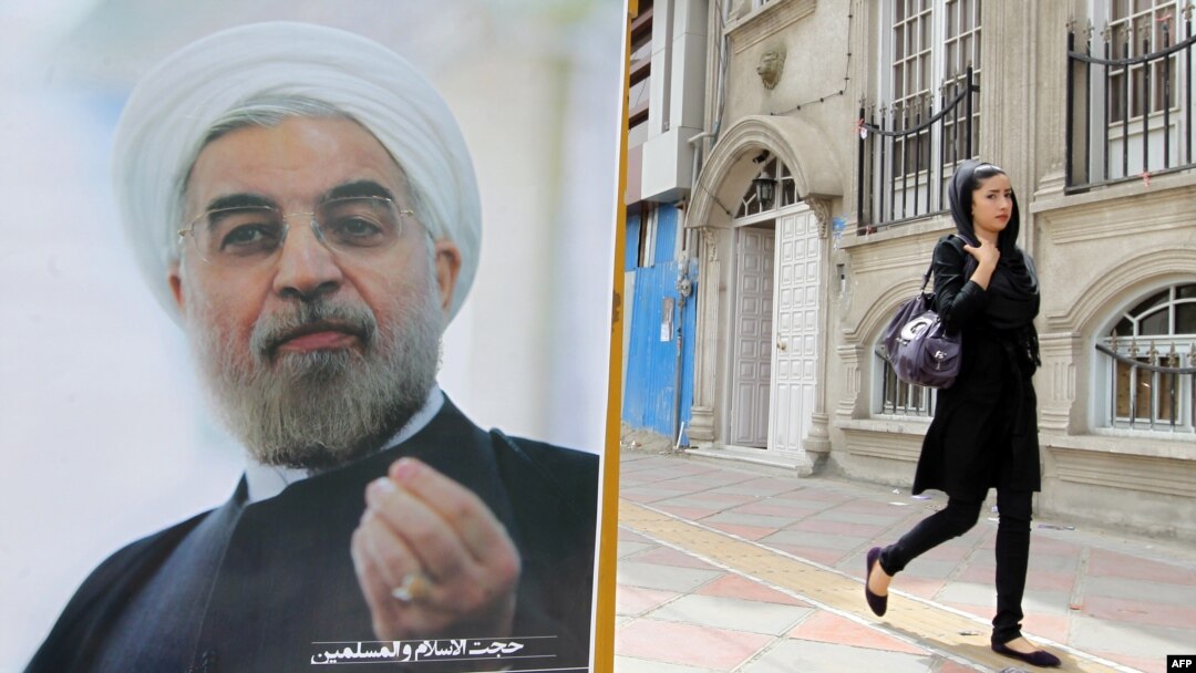 A woman walks past a campaign poster of Hassan Rohani in Tehran ahead of the June election.