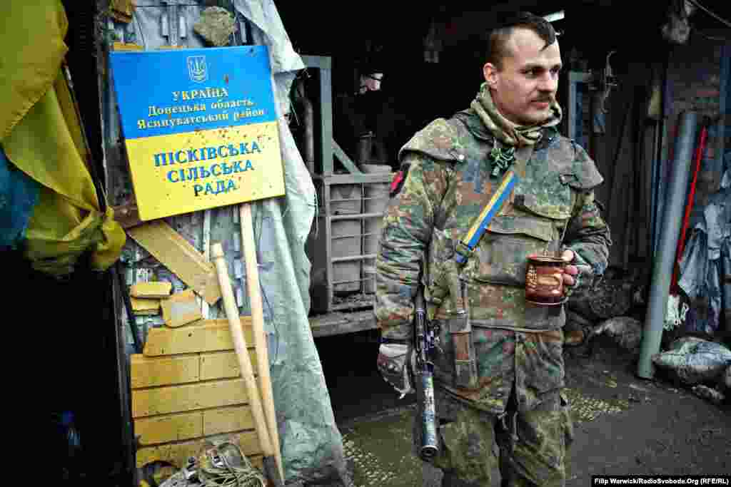 Украинский военный 93-й отдельной механизированной бригады отдыхает за кофе и сигаретой. Знак, снытй военными с Песковского сельского совета, висит на «Позиции 18»