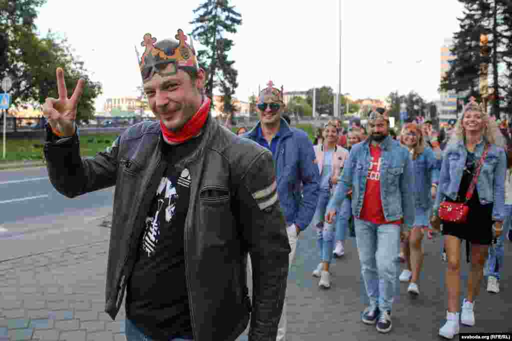 Сотні чалавек рушылі па праспэкце Пераможцаў у накірунку стэлы. Карона — папулярны аксэсуар