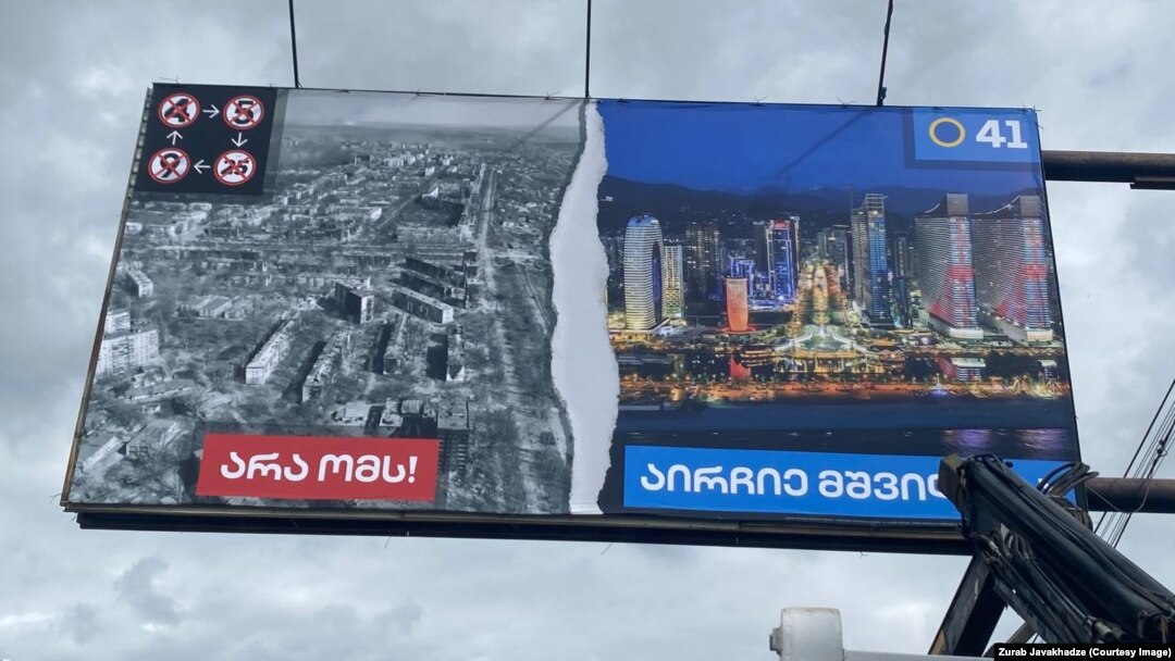 Tbilisinin mərkəzində hakim "Gürcü arzusu" partiyasının reklam lövhəsi. Sol şəklin altında "Müharibəyə yox", sağ tərəfdə "Sülhü seçin" yazılıb.