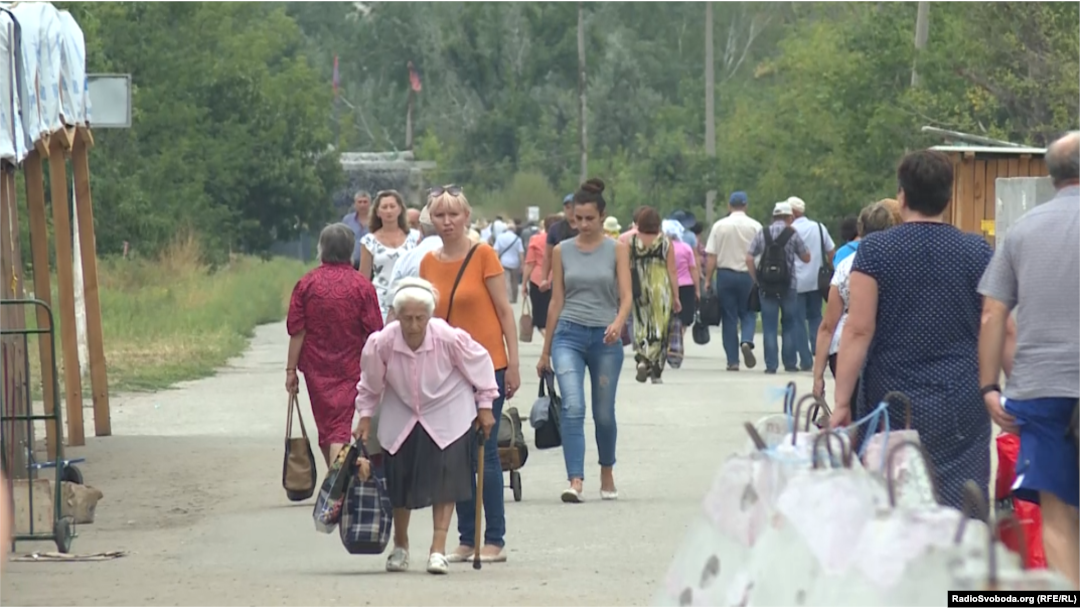 Люди пішки перетинають зруйнований міст, везучи продукти