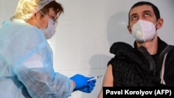 Коронавирус вакцинасын салып жатқан медицина қызметкері.