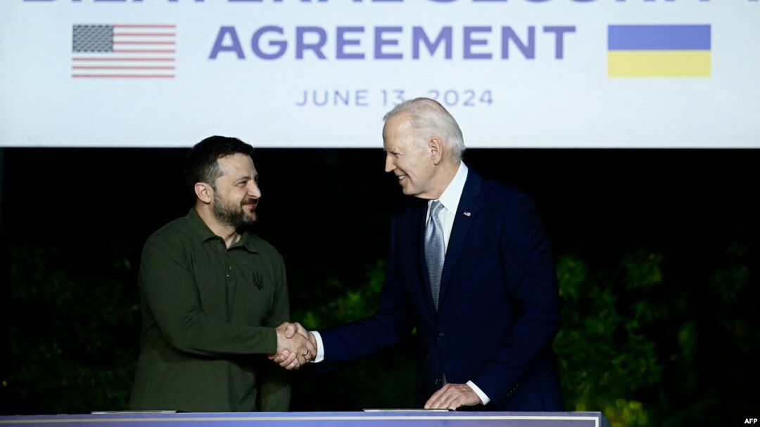 Președintele ucrainean Volodimir Zelenski (stânga) și președintele american Joe Biden semnează un acord bilateral de securitate, 13 iunie 2024, la Summitul G7 din Italia.