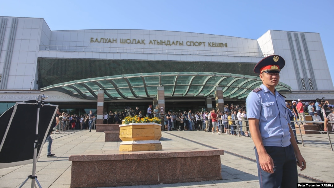 Сотрудник полиции на фоне здания Дворца спорта, где проходит прощание с Денисом Теном. Алматы, 21 июля 2018 года.