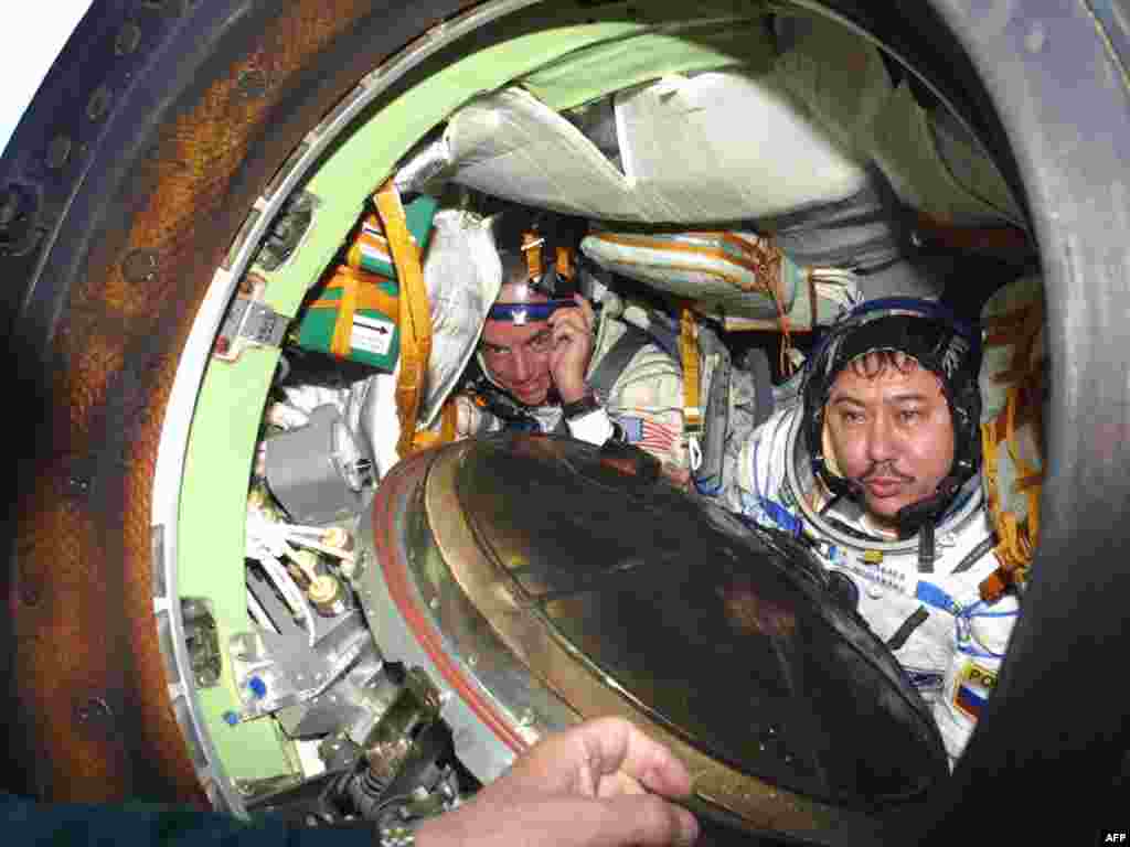 Космонавт Талгат Мусабаев (справа) и космический турист Деннис Тито после приземления посадочной капсулы "Союз". Окрестности города Аркалык, 6 мая 2001 года. 