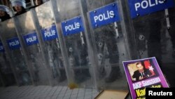 Сотрудники турецкой полиции стоят напротив участников акции протеста. Стамбул, 5 января 2014 года.