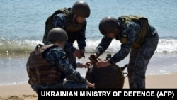 Українські військовослужбовці знешкоджують протикорабельну міну, викинуту на берег штормом. Фото Міністерства оборони України, 16 травня 2022 року.