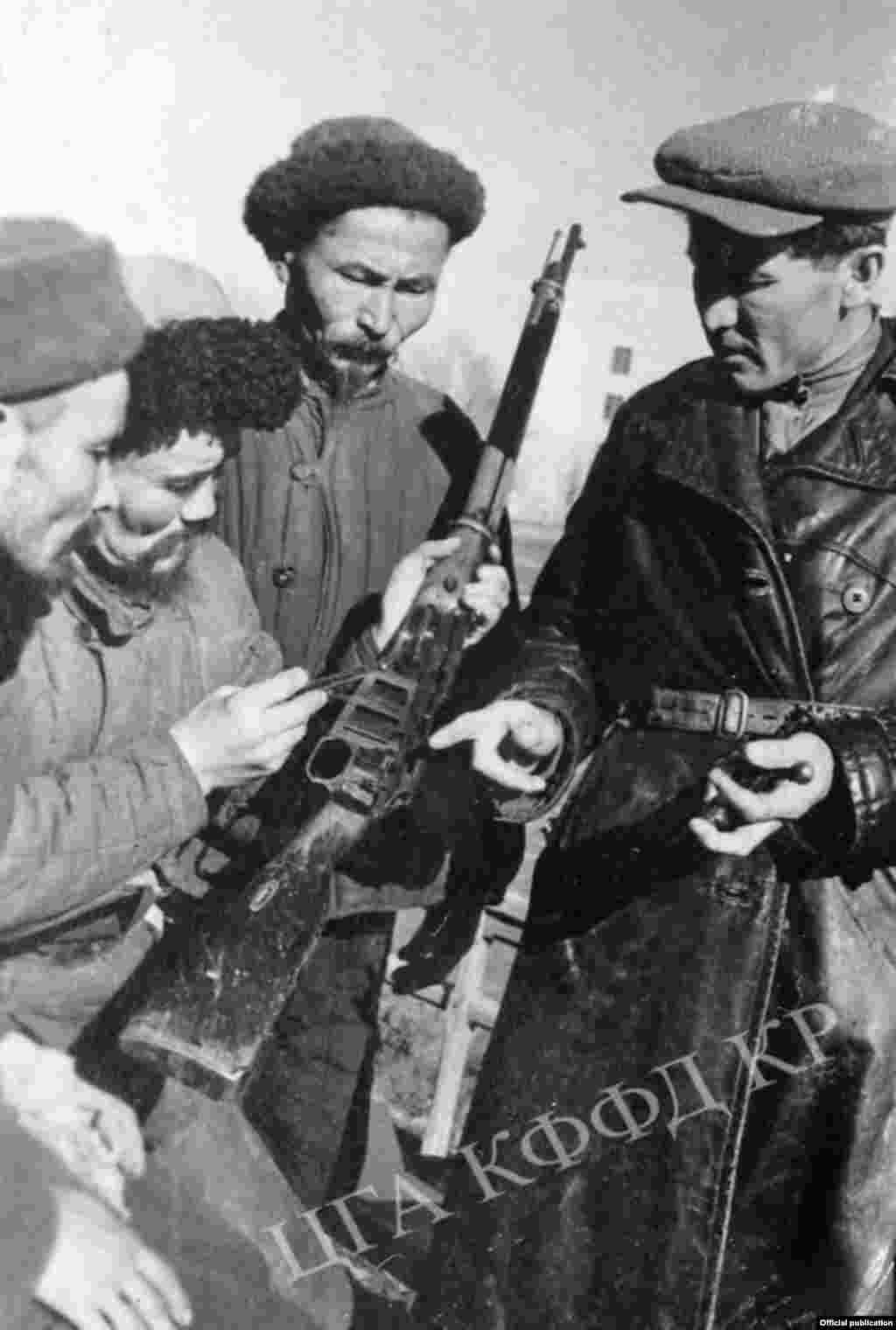 Бойцы всевобуча изучают винтовку (слева на право) Умарбек Умарбаев, Эштай Джанабаев, Джумагул Керимбаев, командир взвода Ханафий Нигматулин. Город Фрунзе. Автор съемки: К.Вильчинский. 1943 год. 