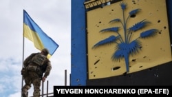 Український військовослужбовець встановлює державний прапор України на адміністративній межі між Харківською і Донецькою областями після звільнення ЗСУ цієї території від військ РФ, 20 вересня 2022 року