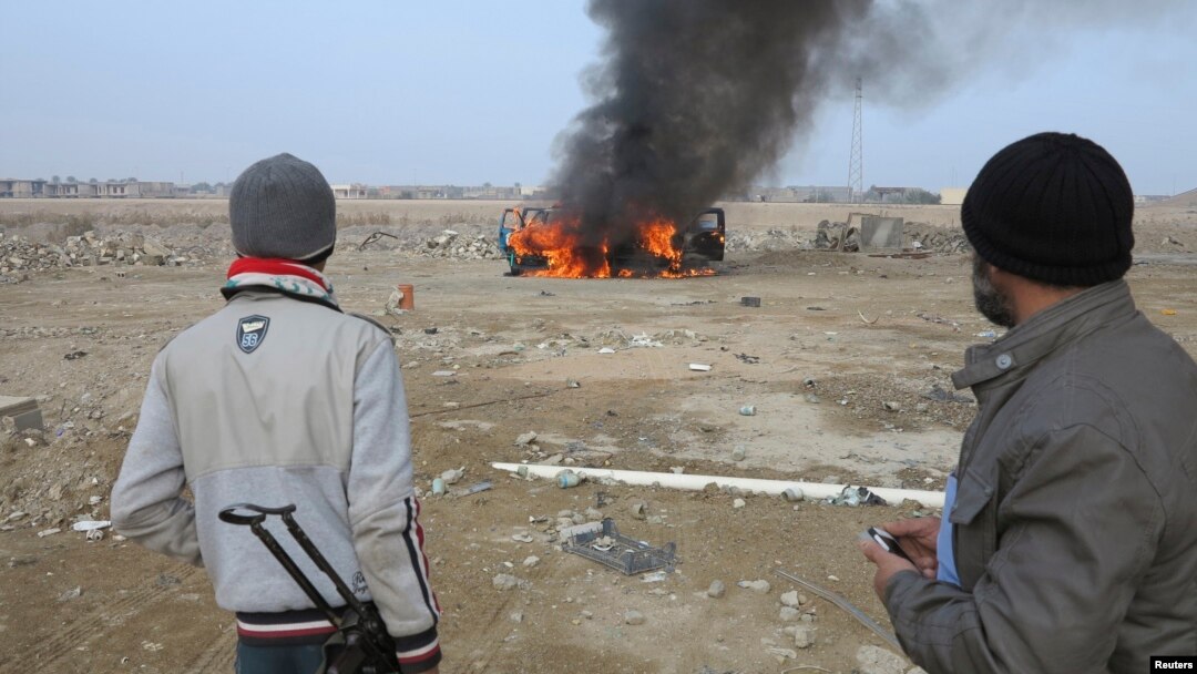 Sunni Muslim fighters watch as a police vehicle burns during clashes in the Iraqi city of Ramadi on January 2. Militants have seized control of large parts of Ramadi and Fallujah amid sectarian violence in recent days. 