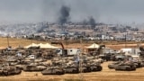 This picture taken from a position in southern Israel on the border with the Gaza Strip shows Israeli tanks and bulldozers deployed as smoke billows over destroyed buildings in Gaza during Israeli bombardment on May 17, 2025.