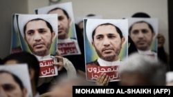 هواداران شیخ علی سلمان، رهبر جمعیت وفاق، در یک تجمع اعتراضی تصاویری از او را بر سر دست دارند.