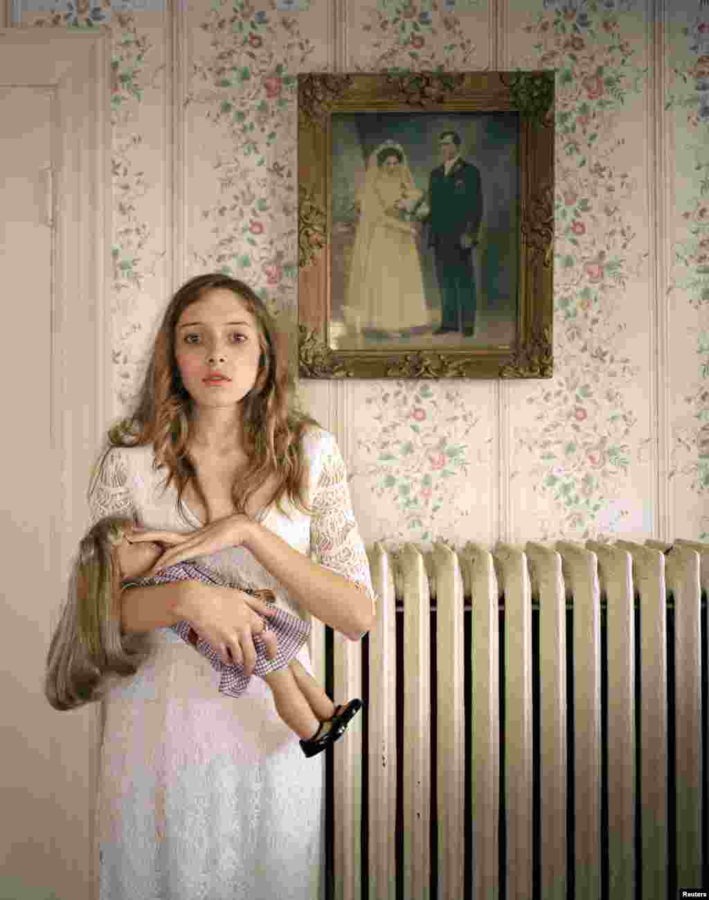 3-е место в категории «Люди. Репортажные портреты. Одиночная фотография». США. «American Girl» – это популярная серия кукол, которые могут выглядеть в точности, как их хозяйка. Кайла позирует с такой куклой возле портрета своих предков. (Ilona Szwarc/Poland/Redux Pictures)