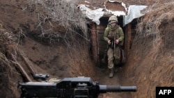 Un militar ucrainean se plimbă într-o tranșee aflată în prima linie, cu separatiștii susținuți de Rusia în apropierea orașului Zolote, în regiunea Luhansk - 8 aprilie 2021.