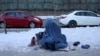 Afganistanka koja drži dijete prosi u Kabulu, Afganistan, 27. januara 2022. 