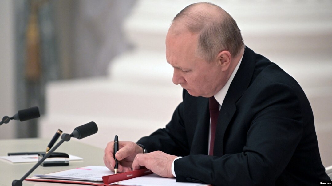Russian President Vladimir Putin signs documents, including a decree recognizing two Russian-backed separatist formations in eastern Ukraine as independent entities during a ceremony in Moscow on February 21. 