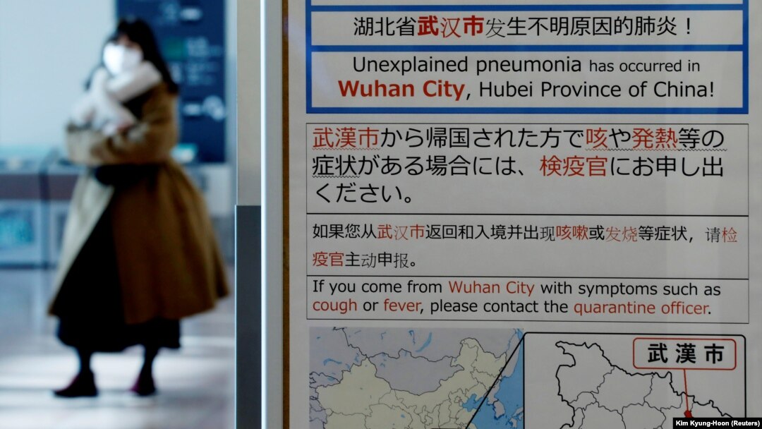 O femeie care poartă o mască trece pe lângă o notificare de carantină despre focarul de coronavirus din Wuhan, China