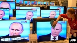 Dükan işgäri Putiniň çykyş edýän wagty teleekrany süpürýär, Moskwa, 17-nji aprel, 2014.