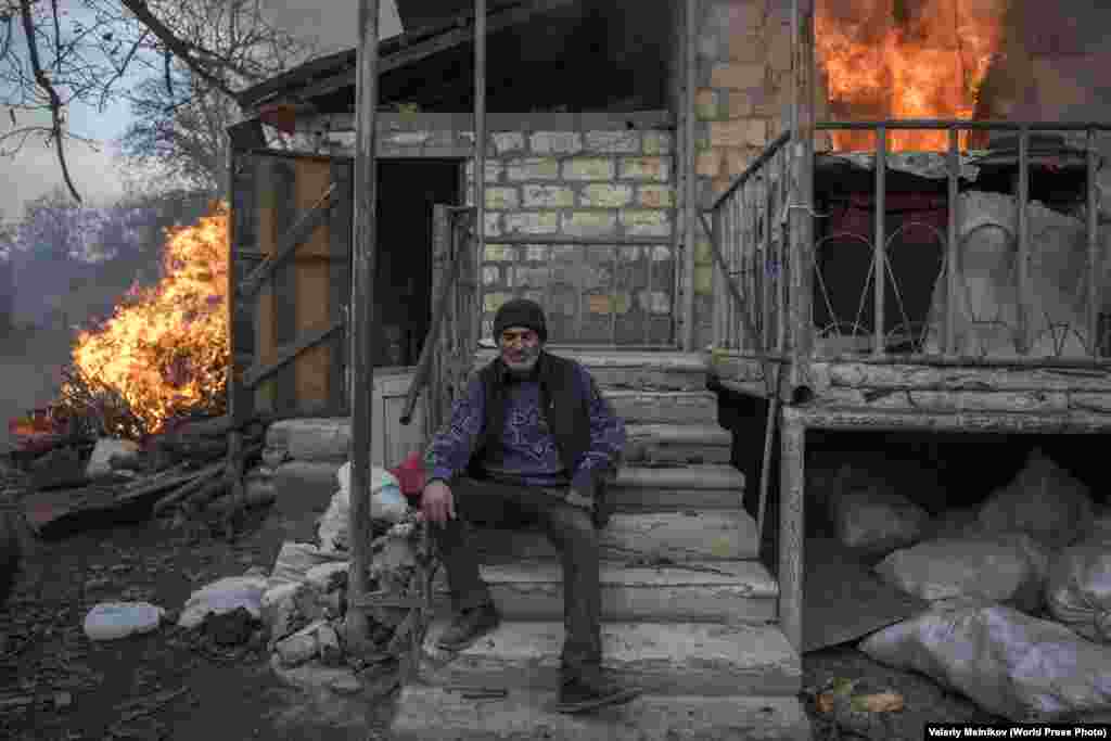 Частина серії під назвою «Втрачений рай». Арег сидить біля палаючого будинку в селі Карегах у Нагірному Карабасі 25 листопада 2020 року. Деякі жителі села спалили свої будинки, перш ніж покинути райони, які поверталися під контроль Азербайджану після листопадової мирної угоди. Загальні новини: Перша премія, історії – Валерій Мельников