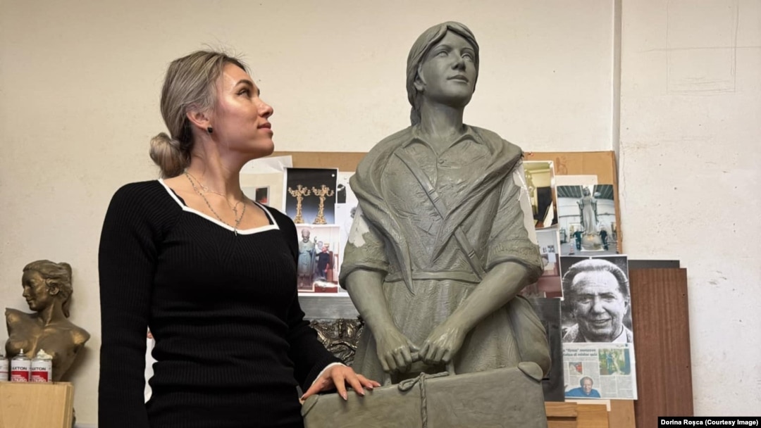 Dorina Roșca pozând alături de monumentul femeii migrante. 